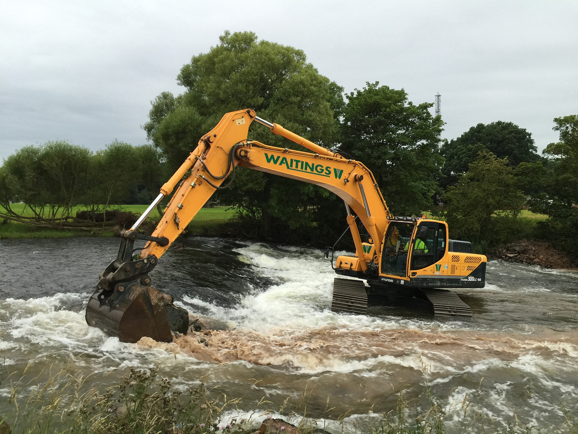 Digger removing rock from the river