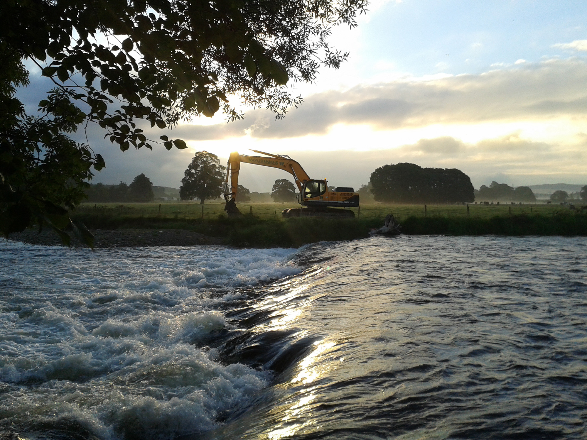 Digger on the riverbank in the sunshine