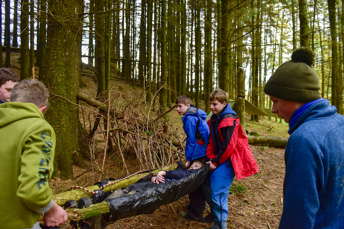 A boy being carried in a makeshift stretcher.