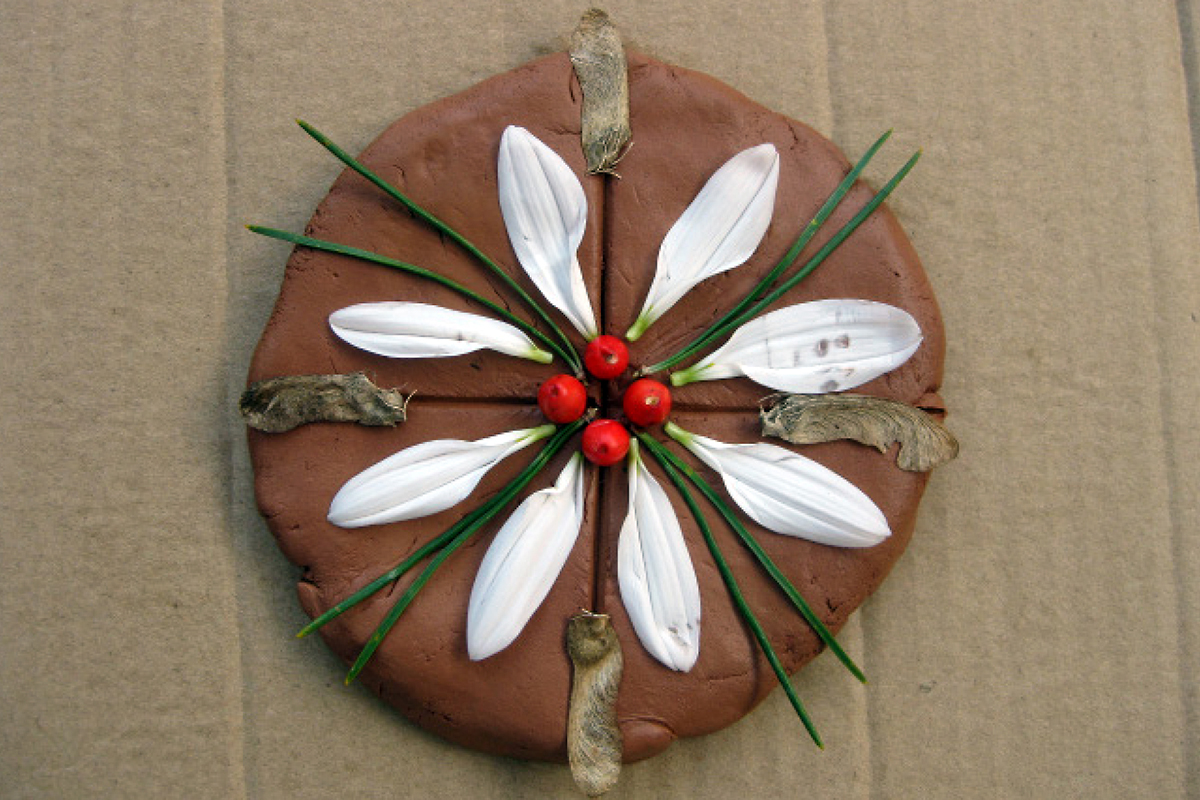 clay circle with a pattern of flower petals, leaves and berries