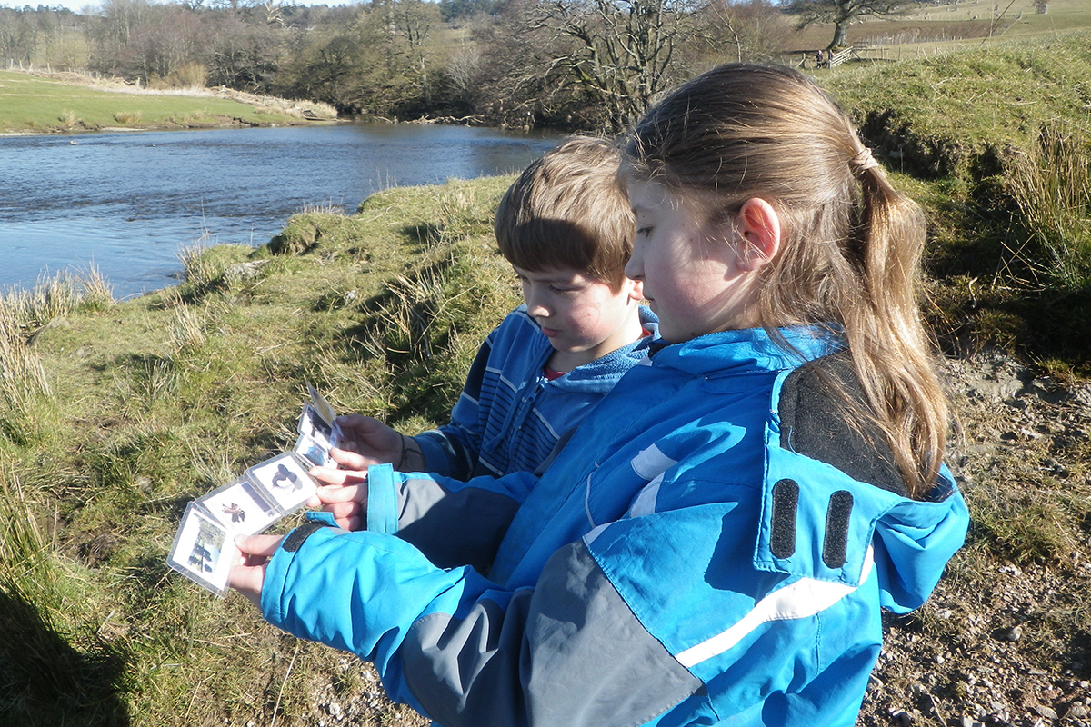 children looking at pictures of things found at the river