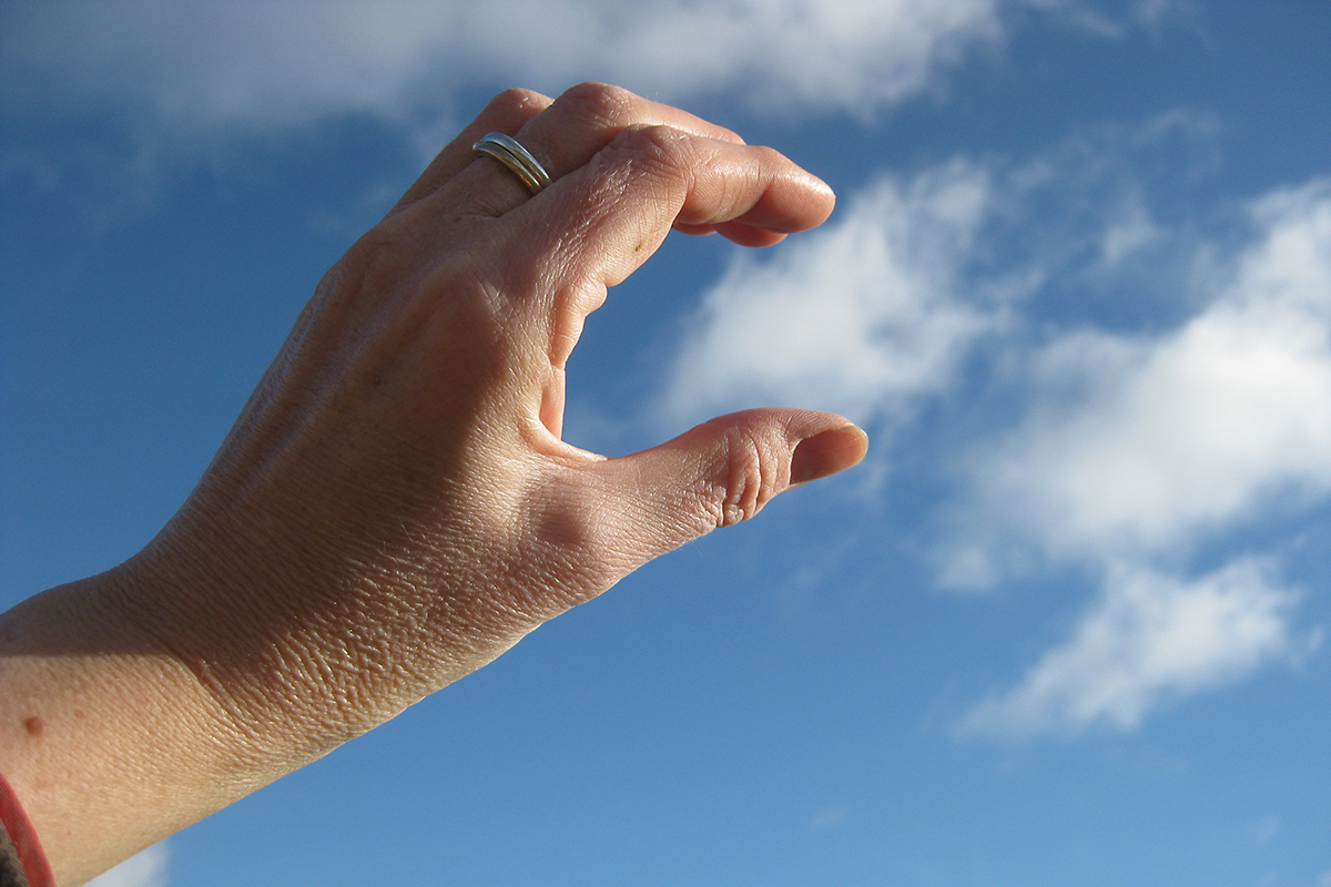 Illusion of a hand touching a cloud in the sky