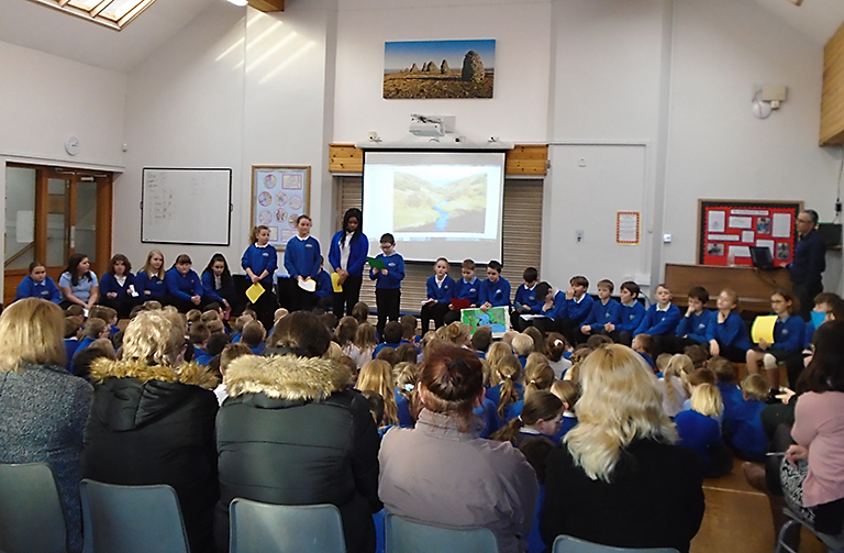 children stood in front of a large group doing an assembly