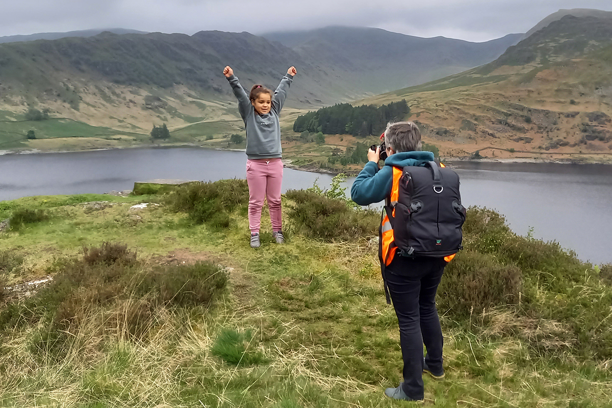 girl with her arms in the air against a backdrop of Haweswater reservoir
