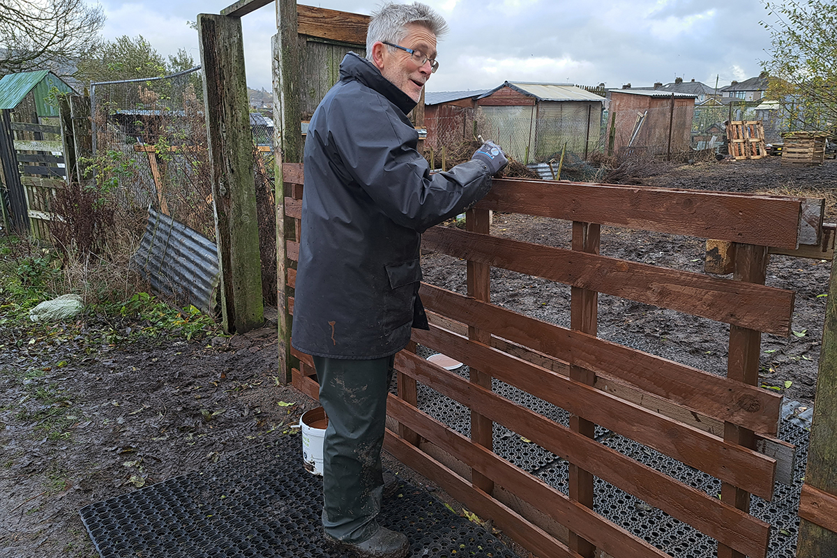 man painting a wooden fence