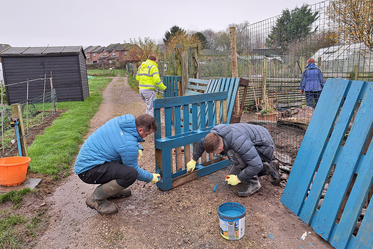 Two men painting a crate blue