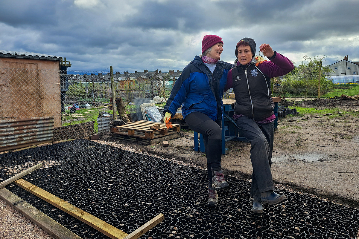 Two women dancing on a plastic layer of paving