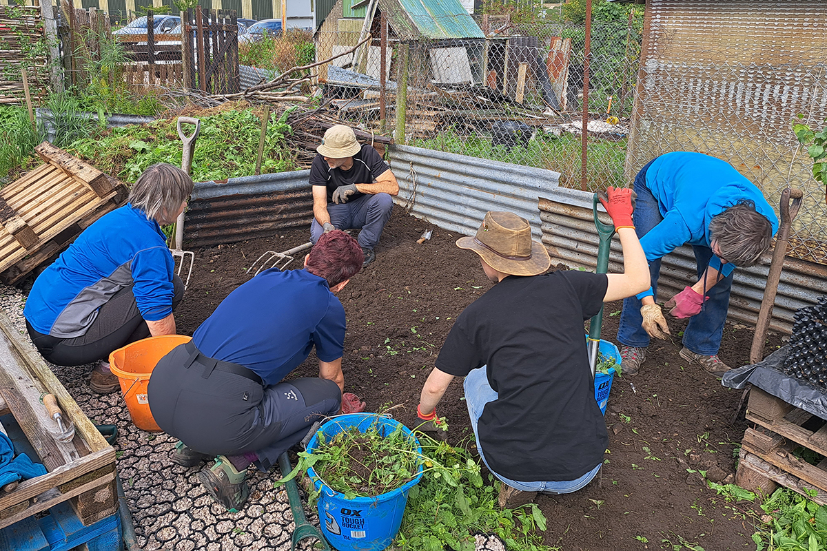 Group of people in a circle digging soil ready to plant trees