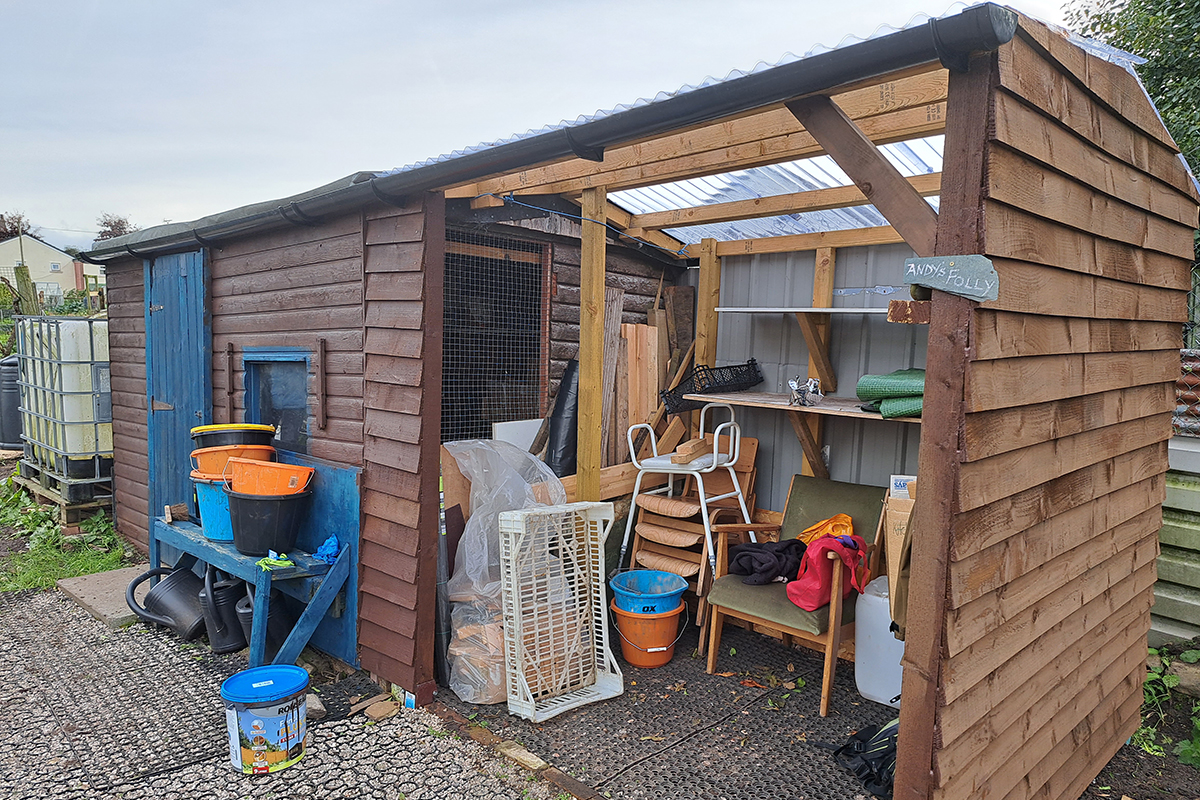 Wooden shed extension with chairs and kit inside.