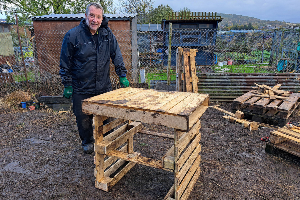 Man with a potting table built out of pallets
