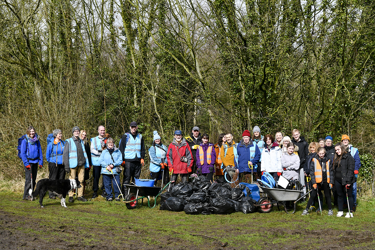 Group of 25 people stood behind some full bin bags