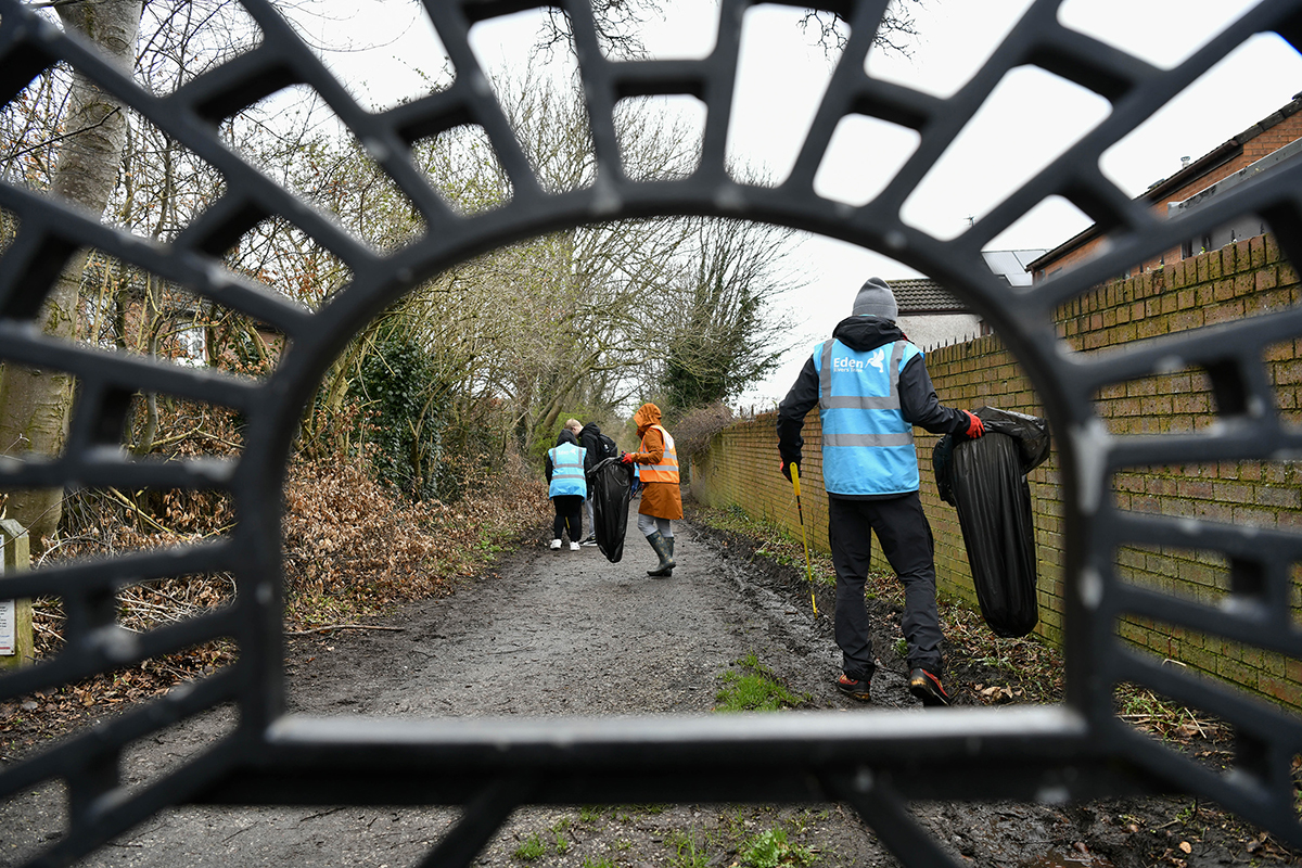 People litter picking, seen through a decorative metal grate