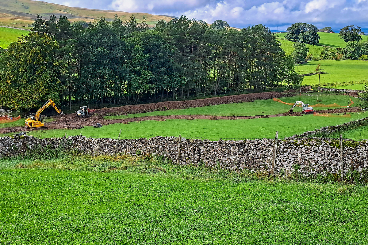 diggers cutting out a new wiggly river channel in a field.